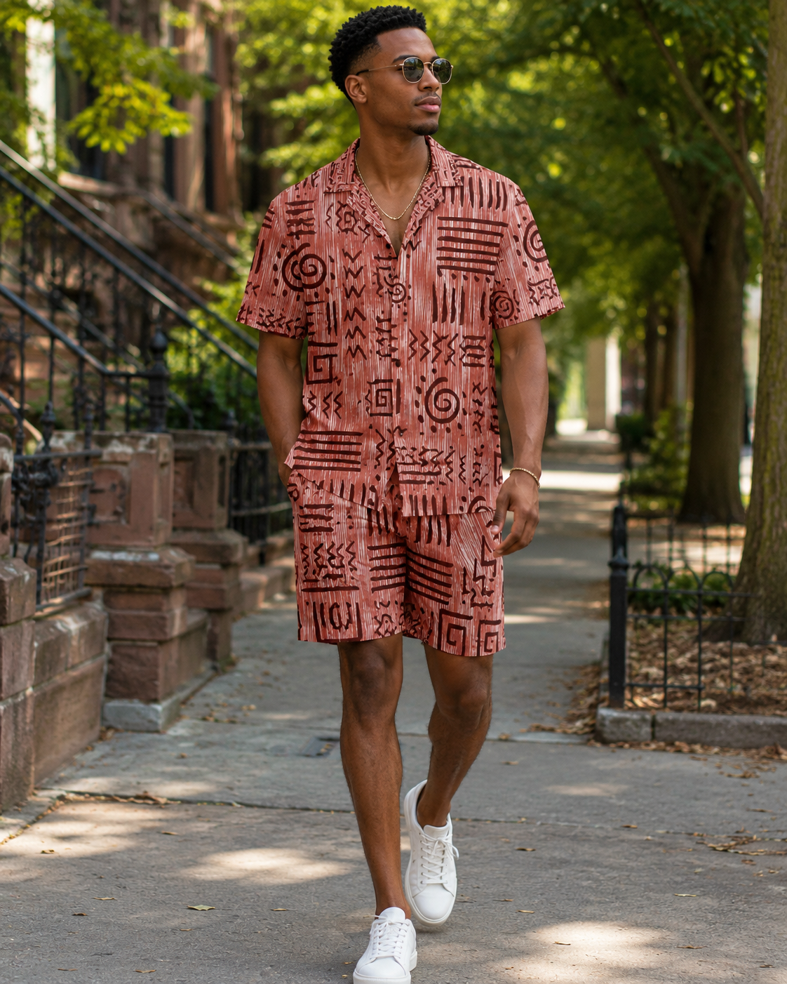 Man wearing a patterned shirt and shorts walking on a sidewalk.