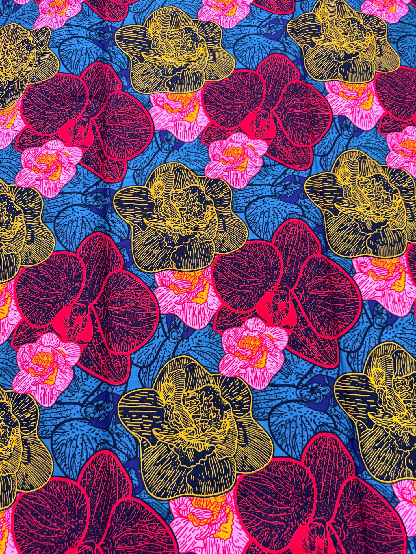 Colorful floral pattern with red, pink, and yellow flowers on a blue background