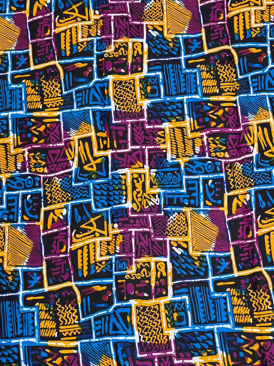 Colorful geometric patterned fabric with blue, yellow, and purple colors.