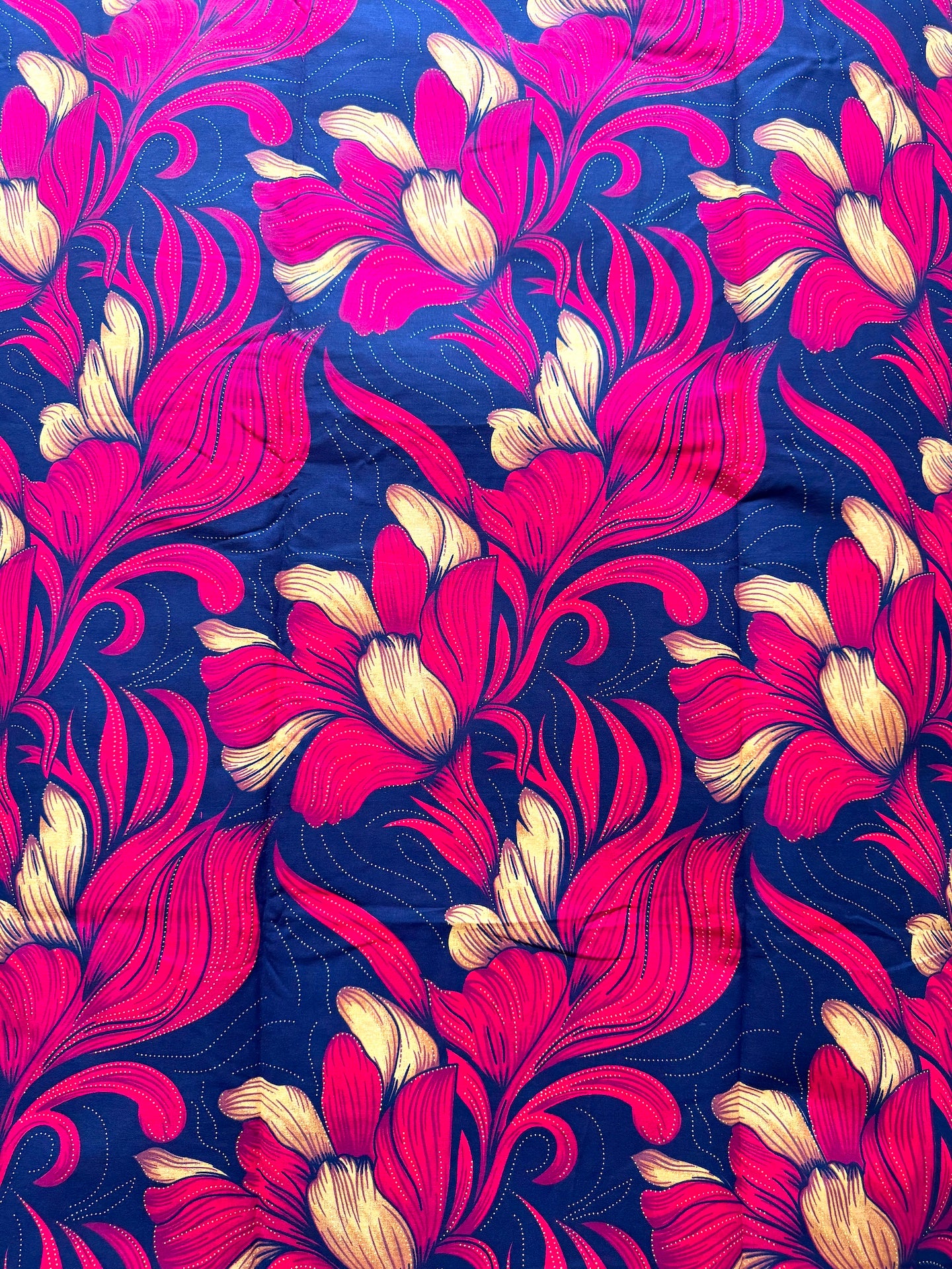 A close-up of a fabric or wallpaper pattern featuring bold, stylized floral motifs in hot pink and cream on a deep navy blue background.