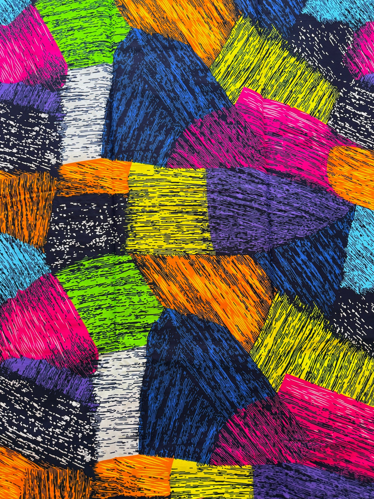 A close-up of a colorful abstract pattern made of irregular polygon shapes in bright pink, blue, green, orange, yellow, purple, black, and white, each filled with textured scribbled lines.