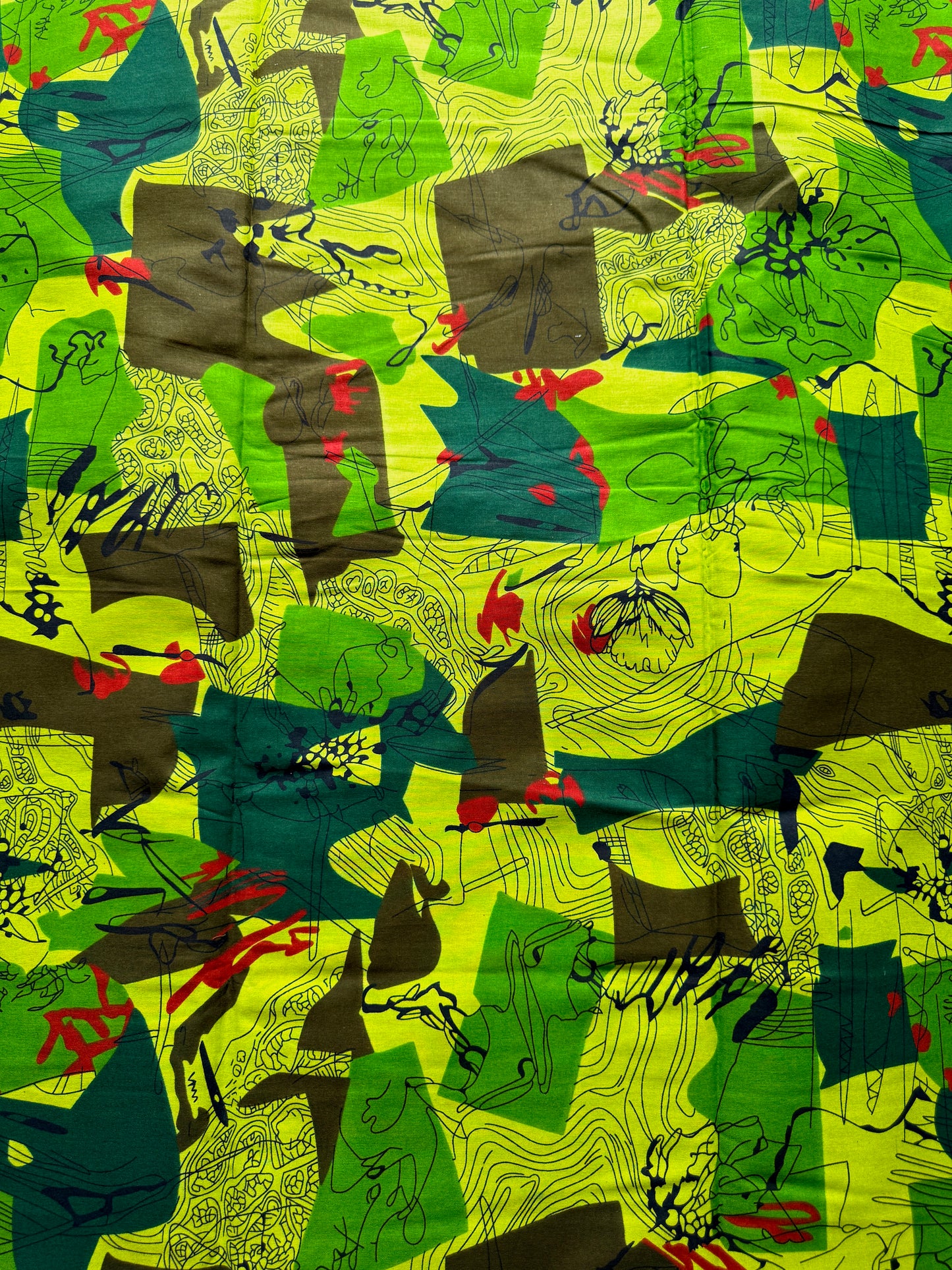 A close-up of a colorful abstract patterned fabric featuring bright lime green, forest green, dark teal, brown, black, and small red accents.
