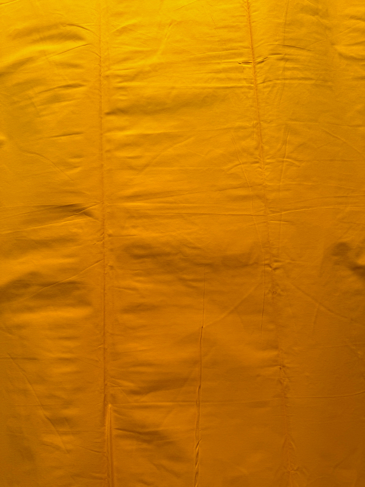 A close-up of a bright yellow-orange fabric with visible folds and texture.