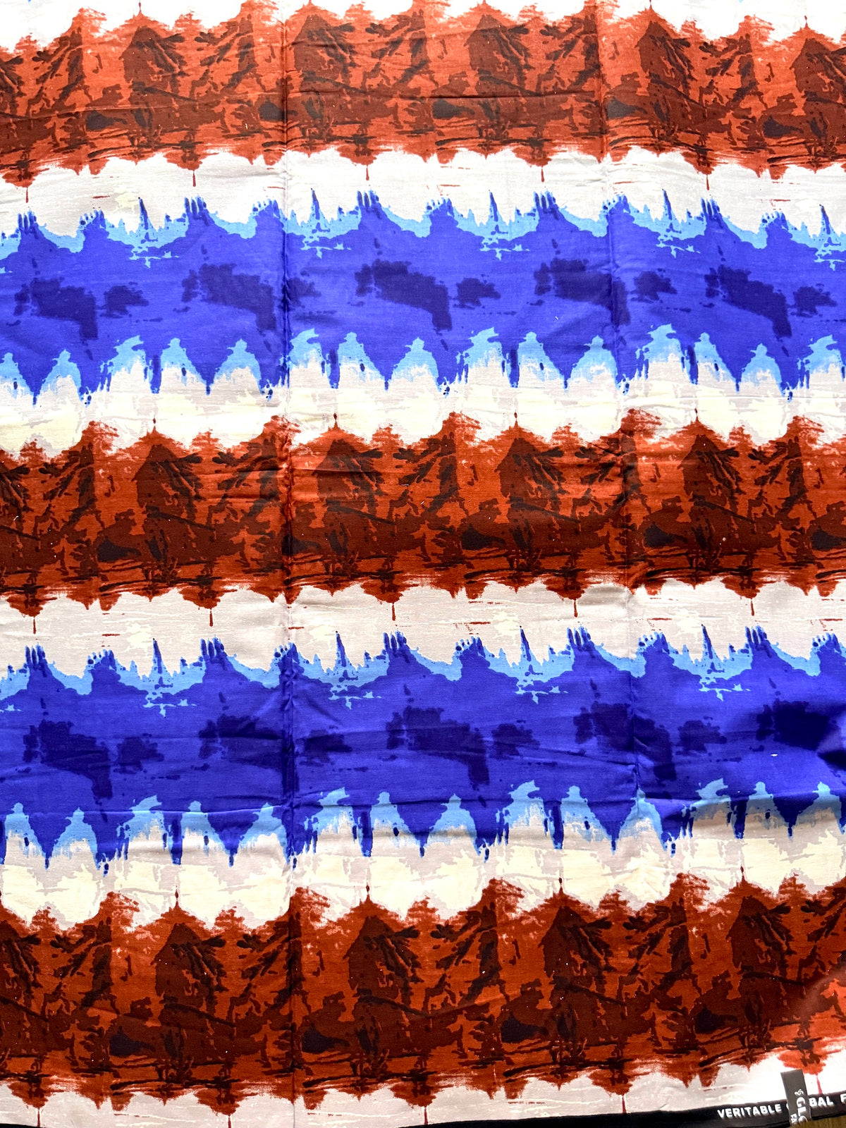 A close-up of a striped fabric or wallpaper pattern with horizontal bands of rust orange, white, and blue, featuring a textured, wavy, brushstroke design.