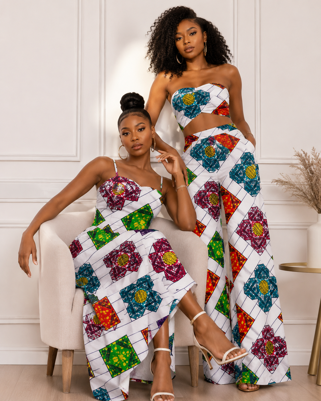 Two women wearing colorful floral-patterned outfits sitting on a chair.