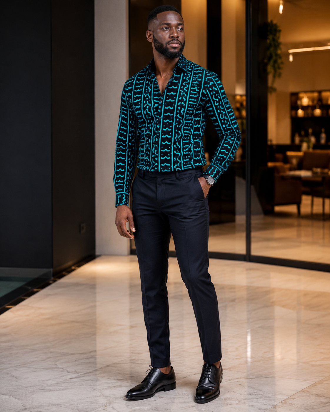 Man wearing a patterned shirt and black pants in an indoor setting