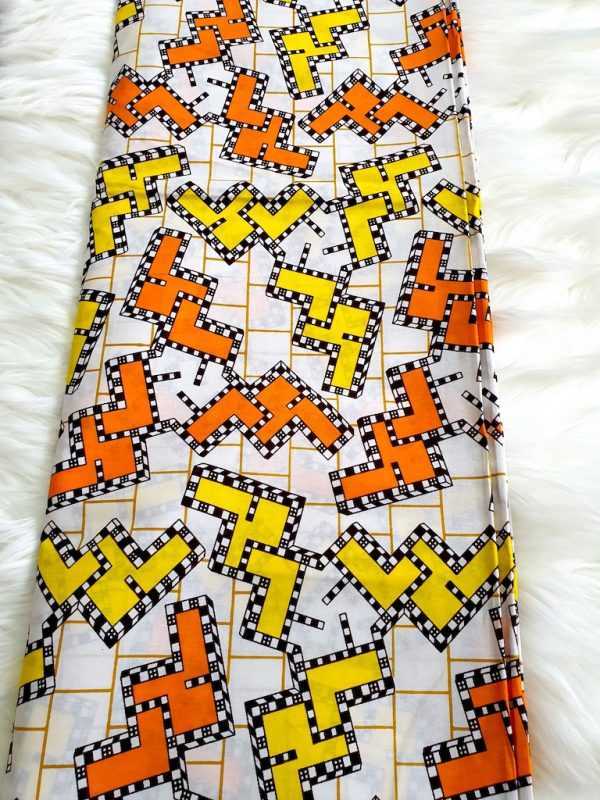 Fabric with geometric pattern featuring orange, yellow, and black on a white background