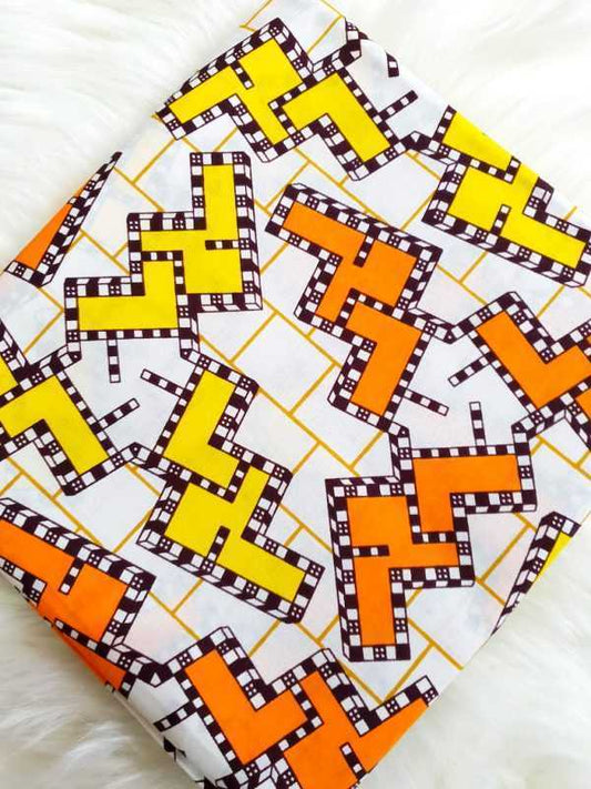 Fabric with geometric pattern of squares in orange, yellow, and white on a white background
