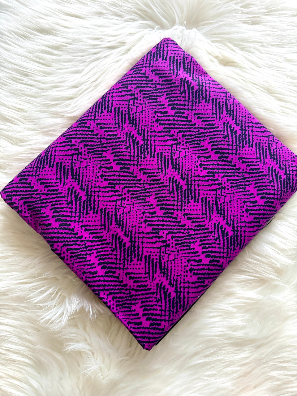 Purple fabric with black pattern on a white fluffy surface