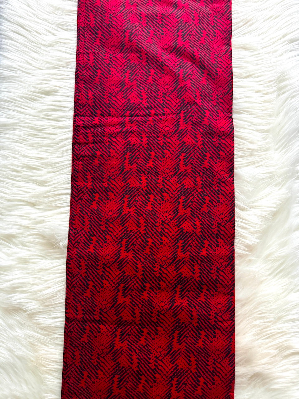 Red and black patterned tie on a white fluffy surface