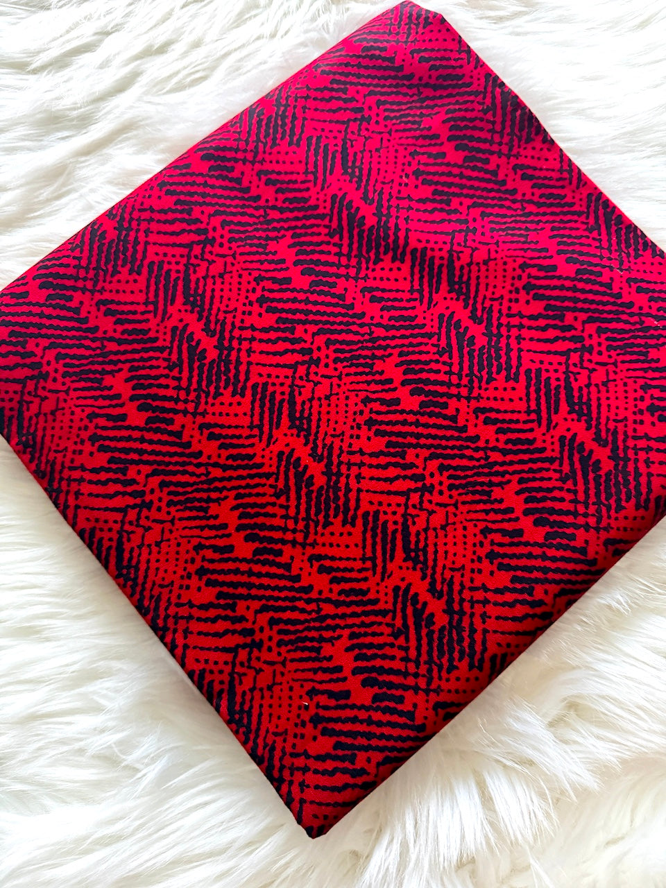 Red and black patterned fabric on a white fluffy surface
