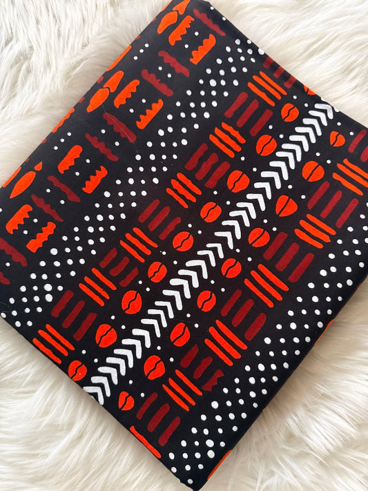 Patterned fabric with red, white, and black designs on a fluffy white surface