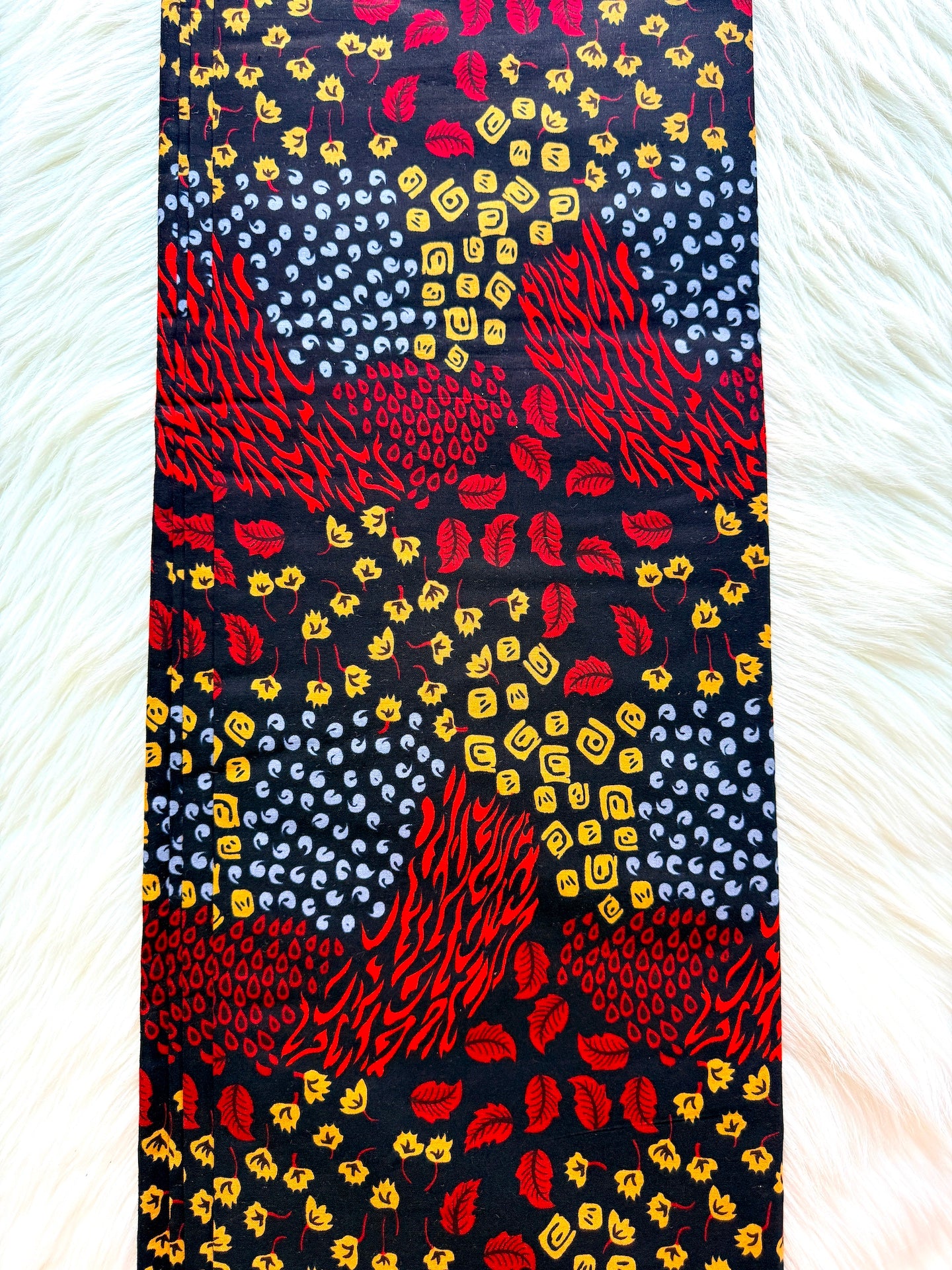 Colorful patterned fabric with red, yellow, and blue designs on a dark background.