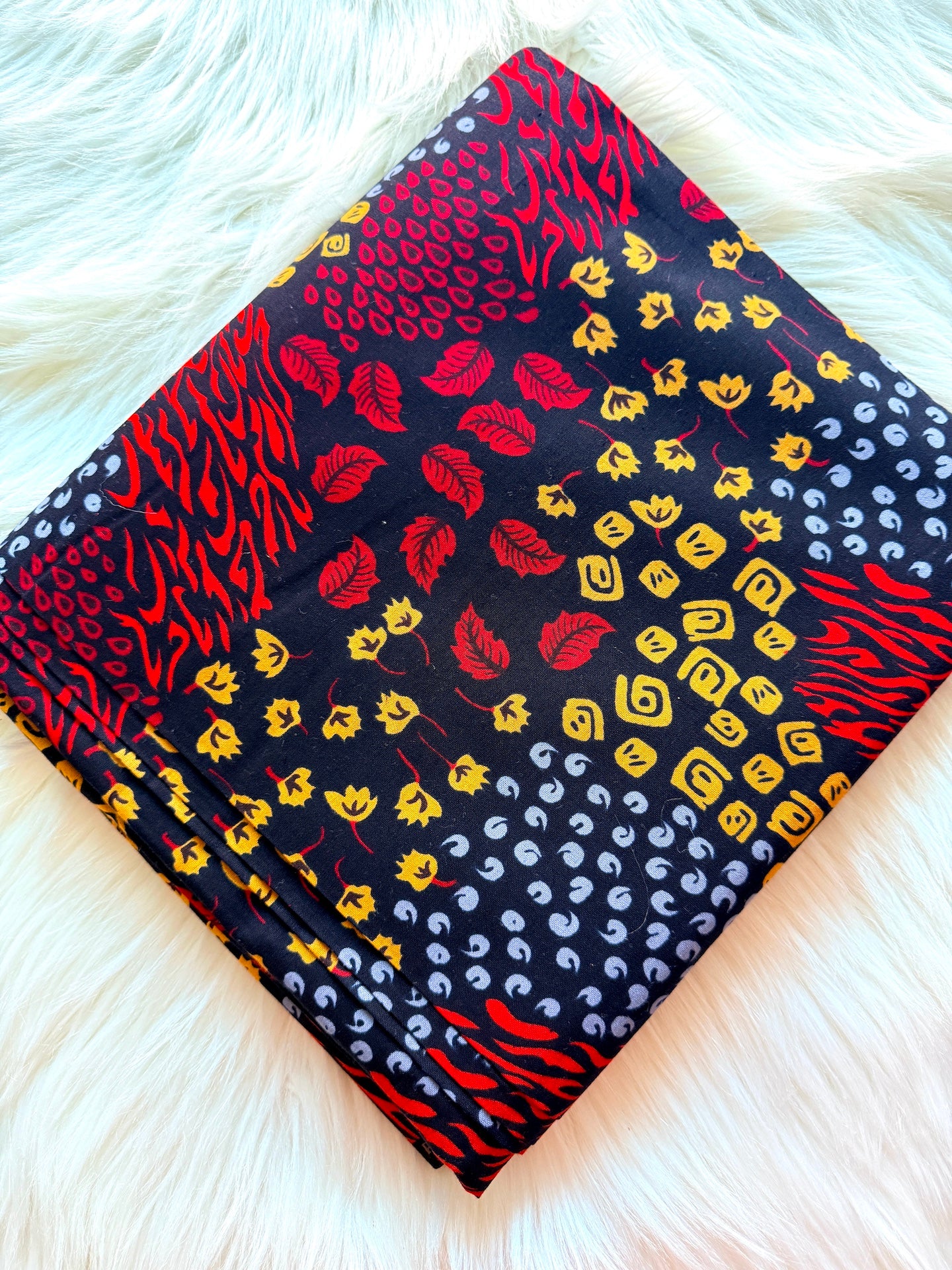 Stack of patterned fabric swatches on a white fur surface
