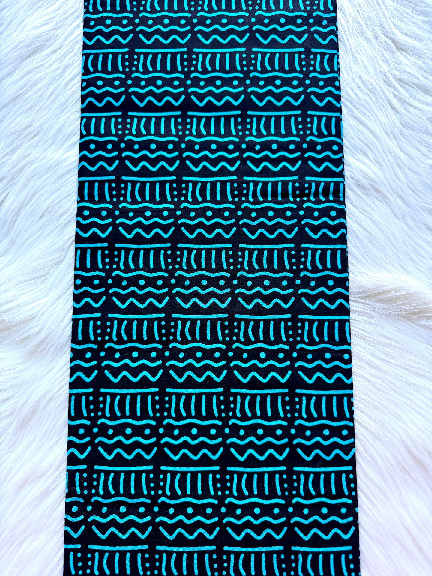 Black and blue patterned fabric on a white fur background