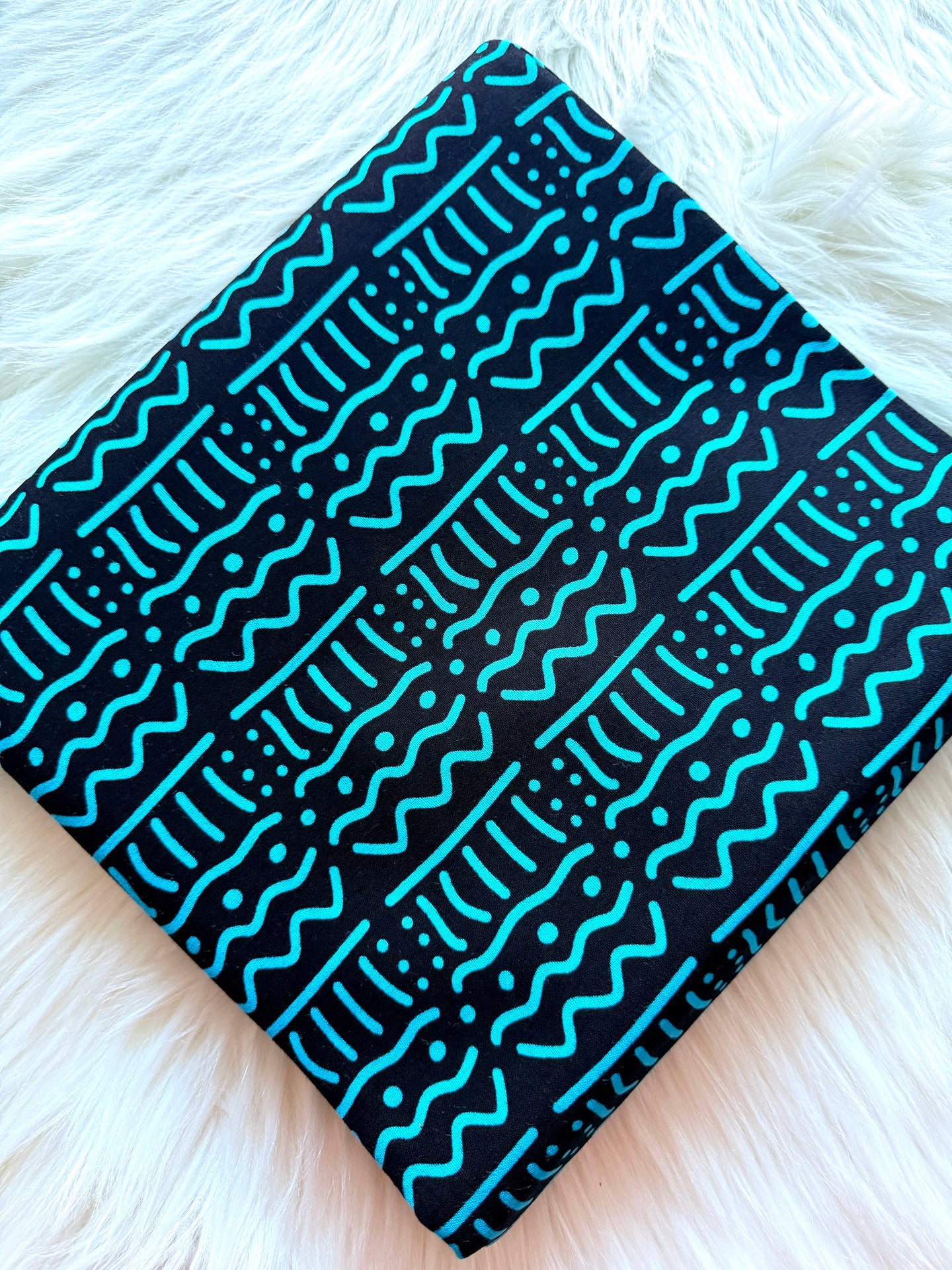 Black fabric with blue patterns on a white fluffy surface