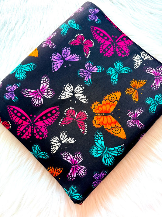 Colorful butterfly pattern on a black background with fringe edges.