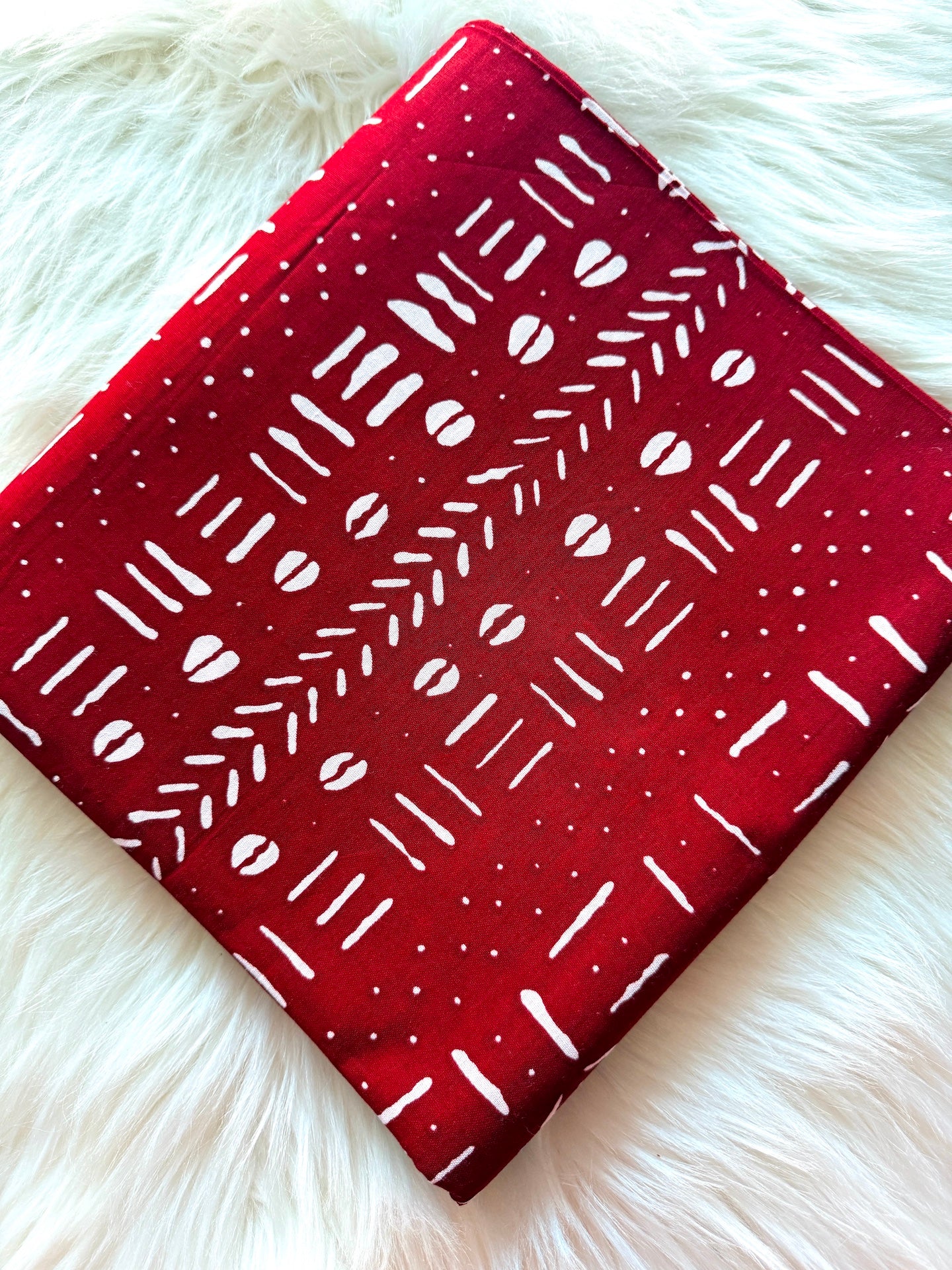 Red fabric with white patterns on a fluffy white surface