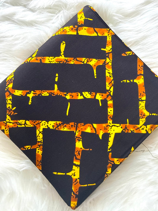 Black fabric with orange and yellow abstract pattern on a white textured background