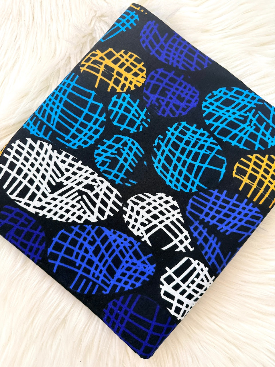 Fabric with blue, yellow, and white abstract patterns on a black background