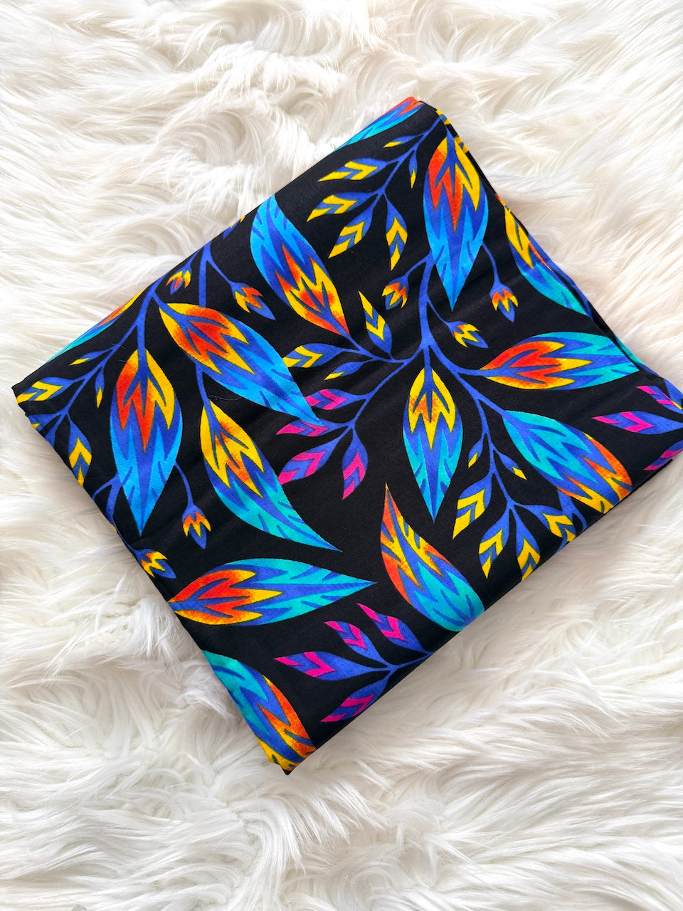 Colorful leaf patterned fabric on a white fluffy surface