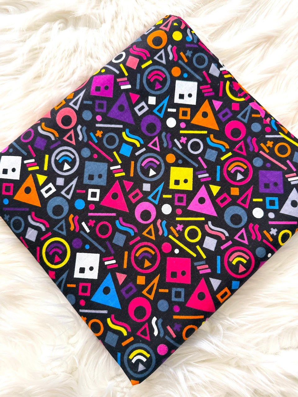 Colorful geometric patterned blanket on a white fluffy surface
