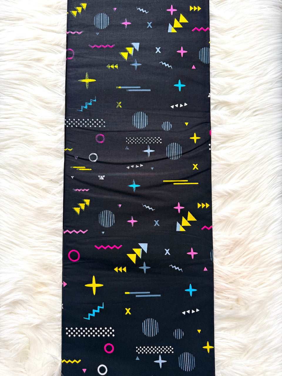 Black leggings with colorful geometric pattern on a white textured surface