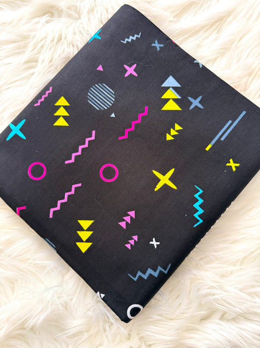 Black fabric with colorful geometric patterns on a white fluffy surface
