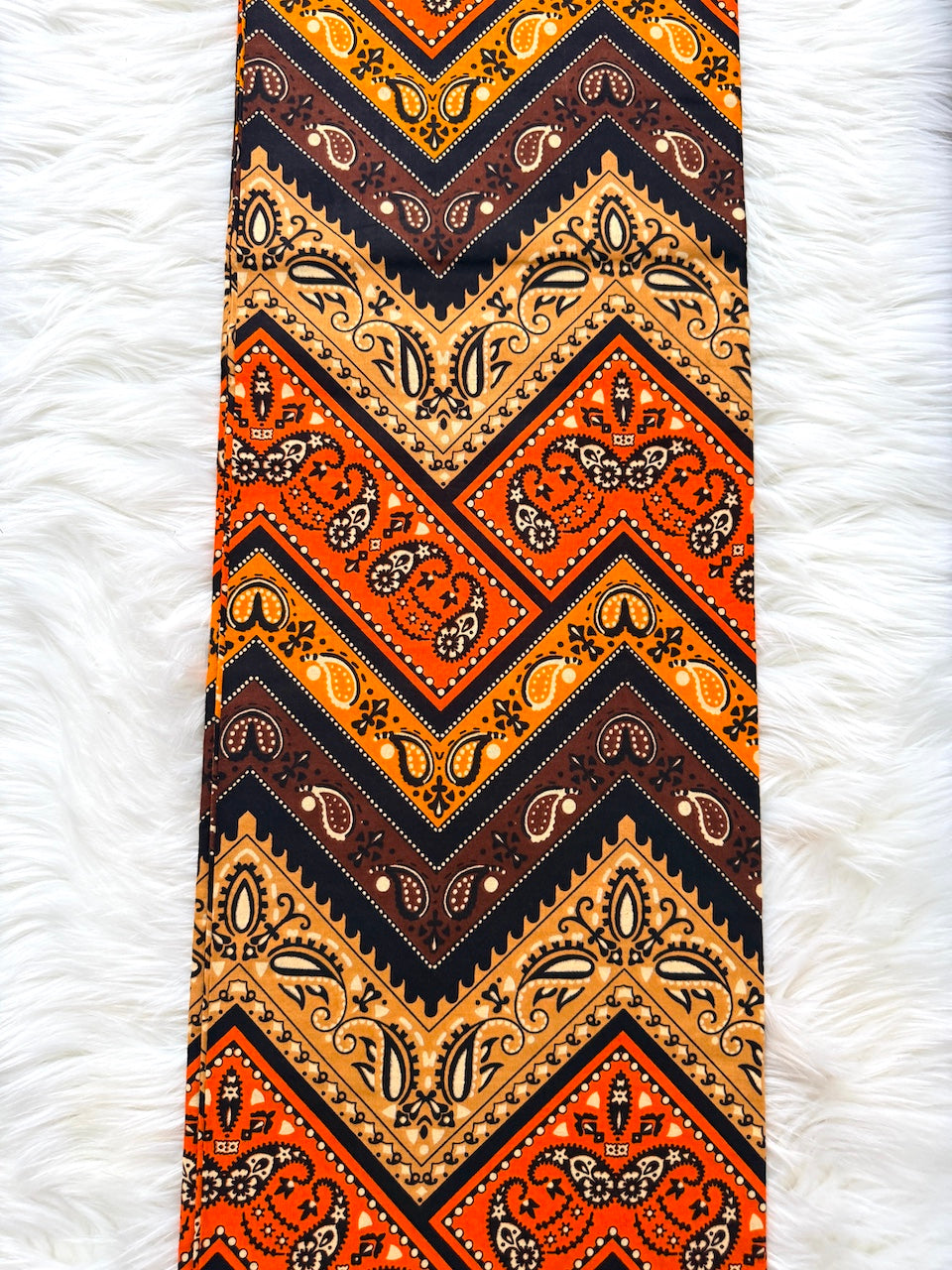 Patterned tie with orange, black, and beige design on a white fur background