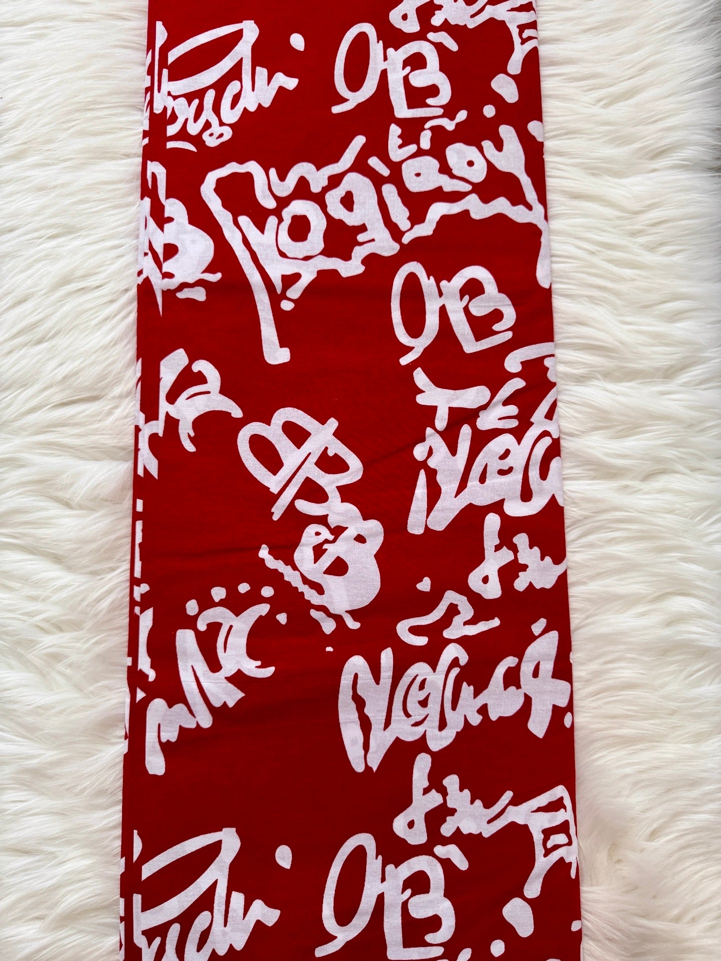 Red bandana with white text and logos on a white fluffy surface