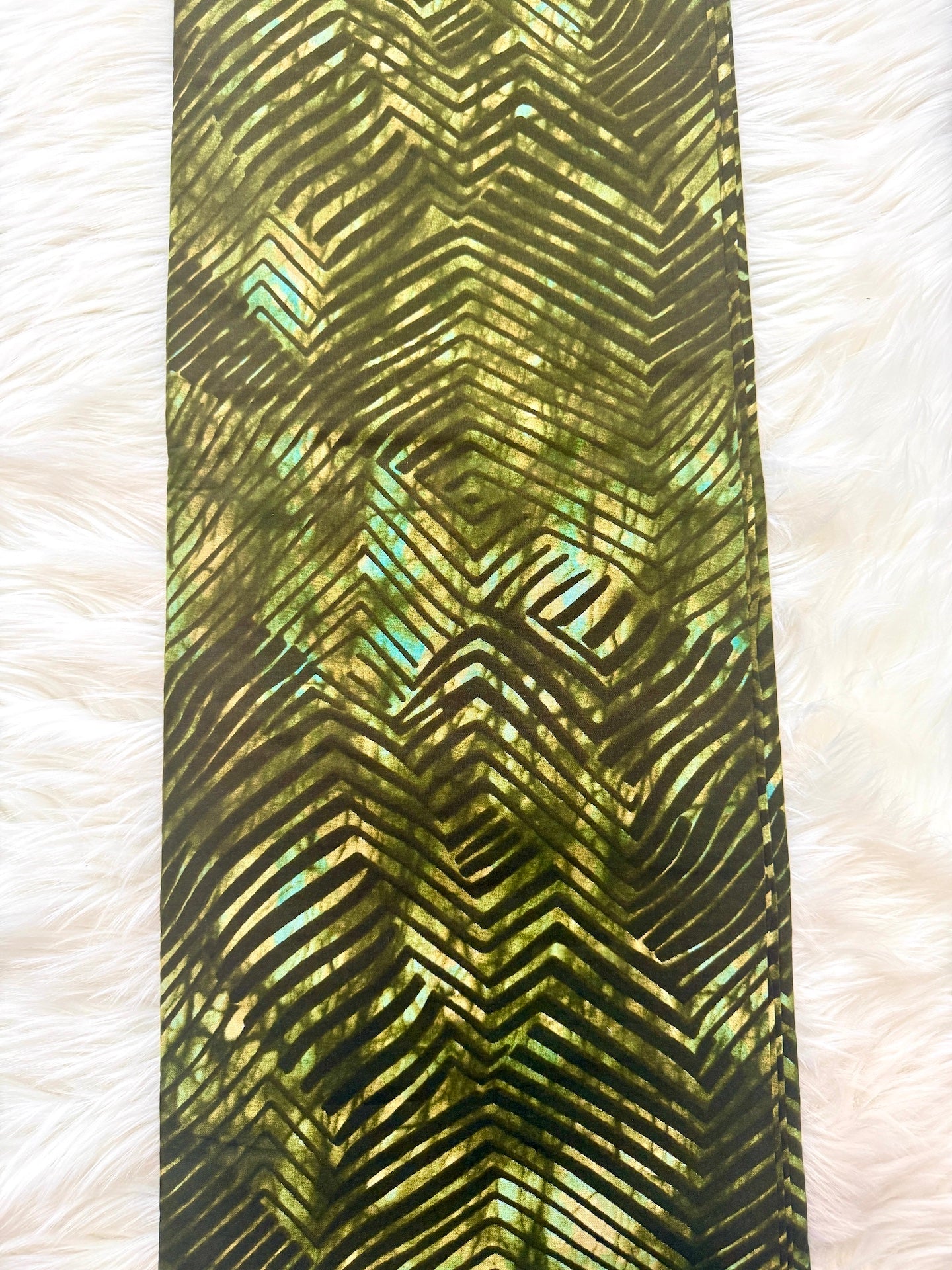 Green and black patterned fabric on a white textured background