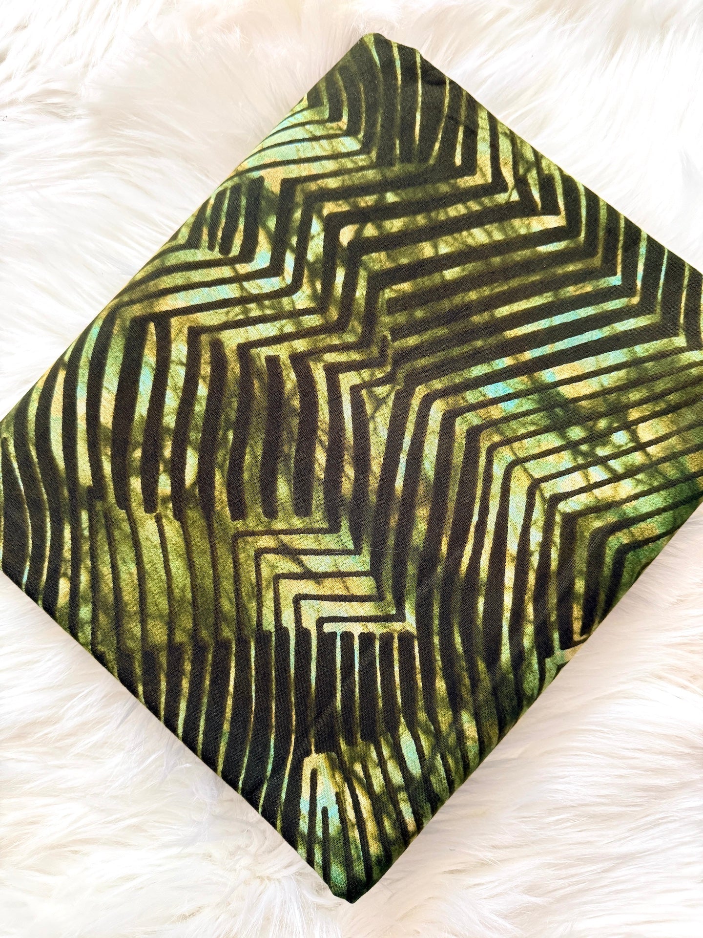 Green and black patterned fabric on a white textured background