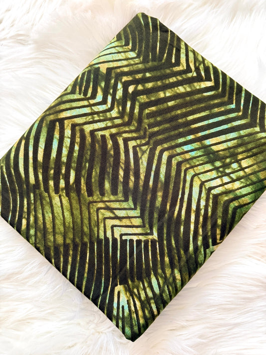 Green and black patterned fabric on a white textured background