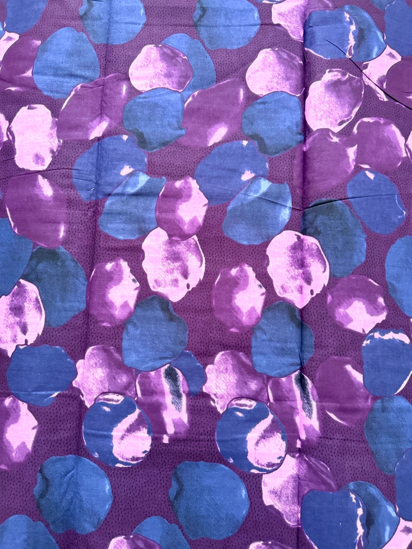 Patterned fabric with blue and purple shapes on a purple background