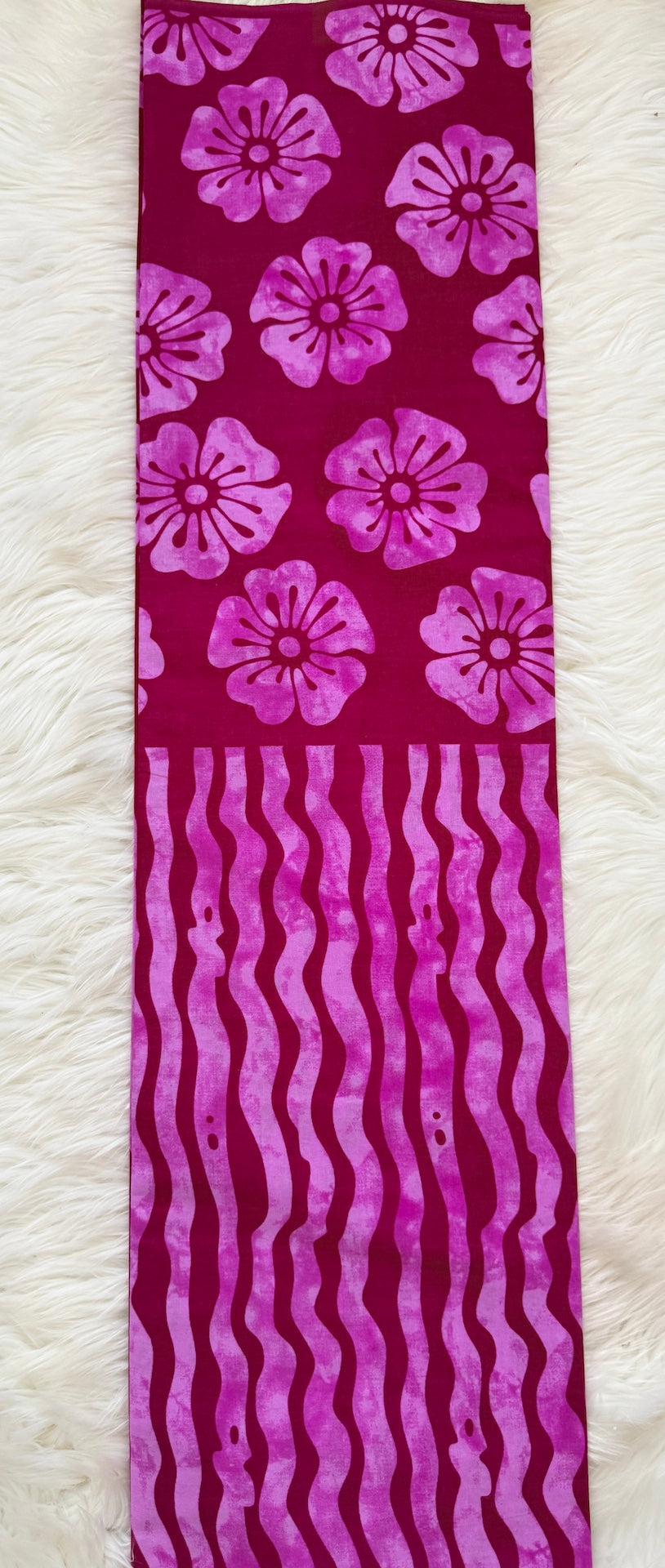 Strip of fabric with purple floral and wavy patterns on a white background
