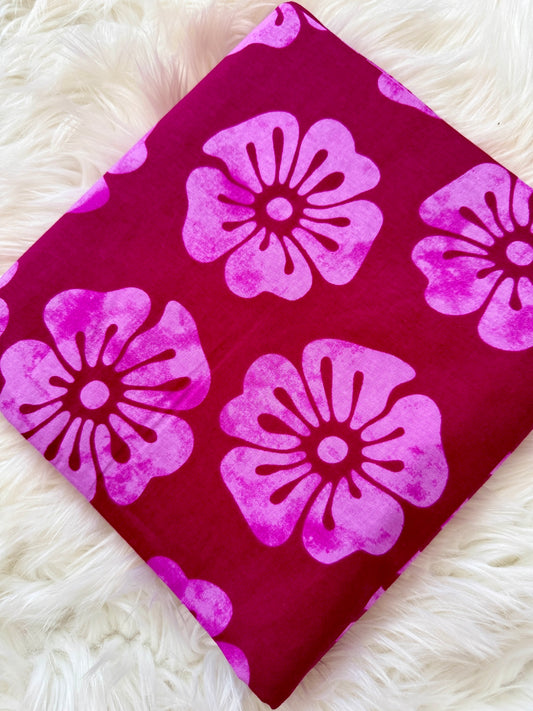 Pink floral pattern on a red fabric swatch against a white fluffy background
