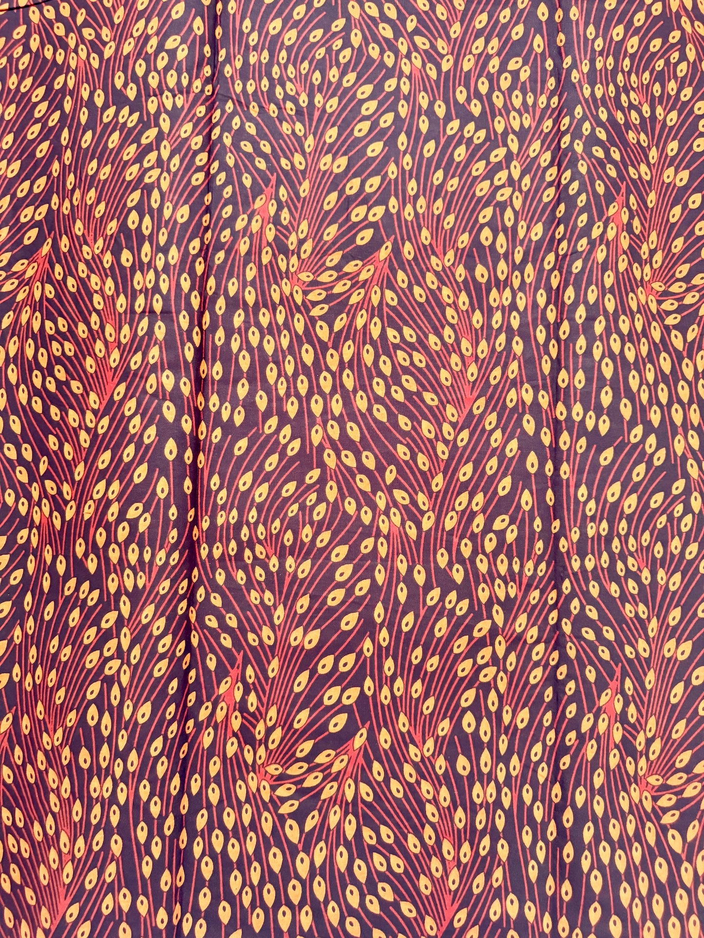 Patterned fabric with a repeating design of orange and red shapes on a purple background