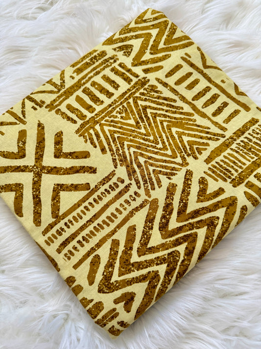 Decorative square pillow with gold geometric pattern on a white fluffy surface