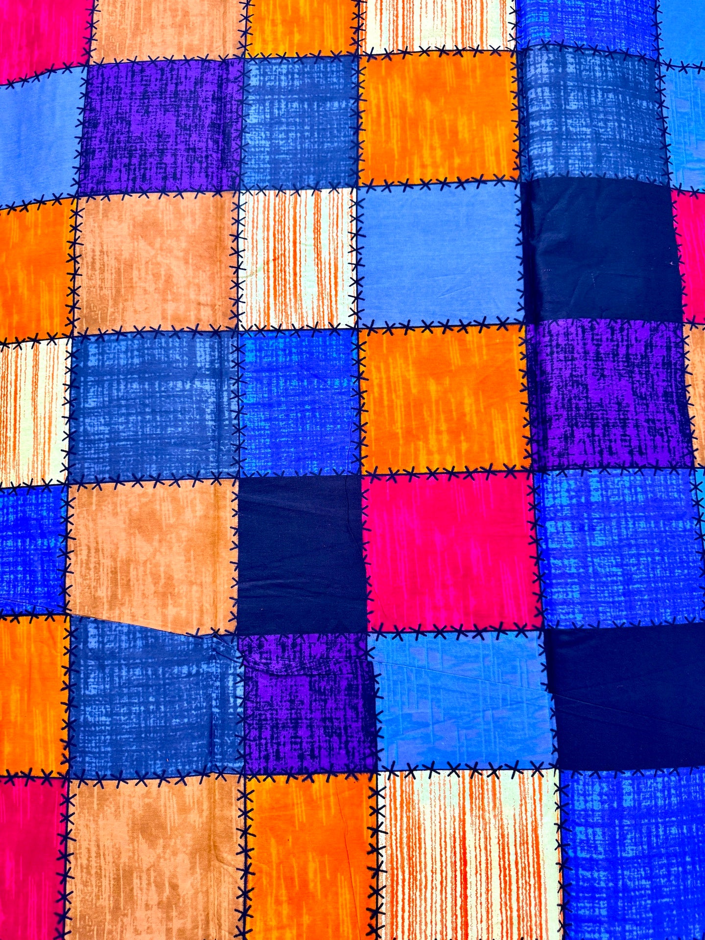 Colorful patchwork quilt with square patterns in various bright colors.