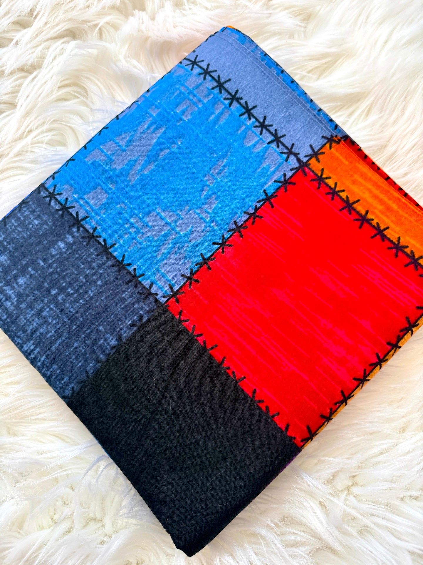 Colorful quilt with geometric pattern on a white fluffy surface