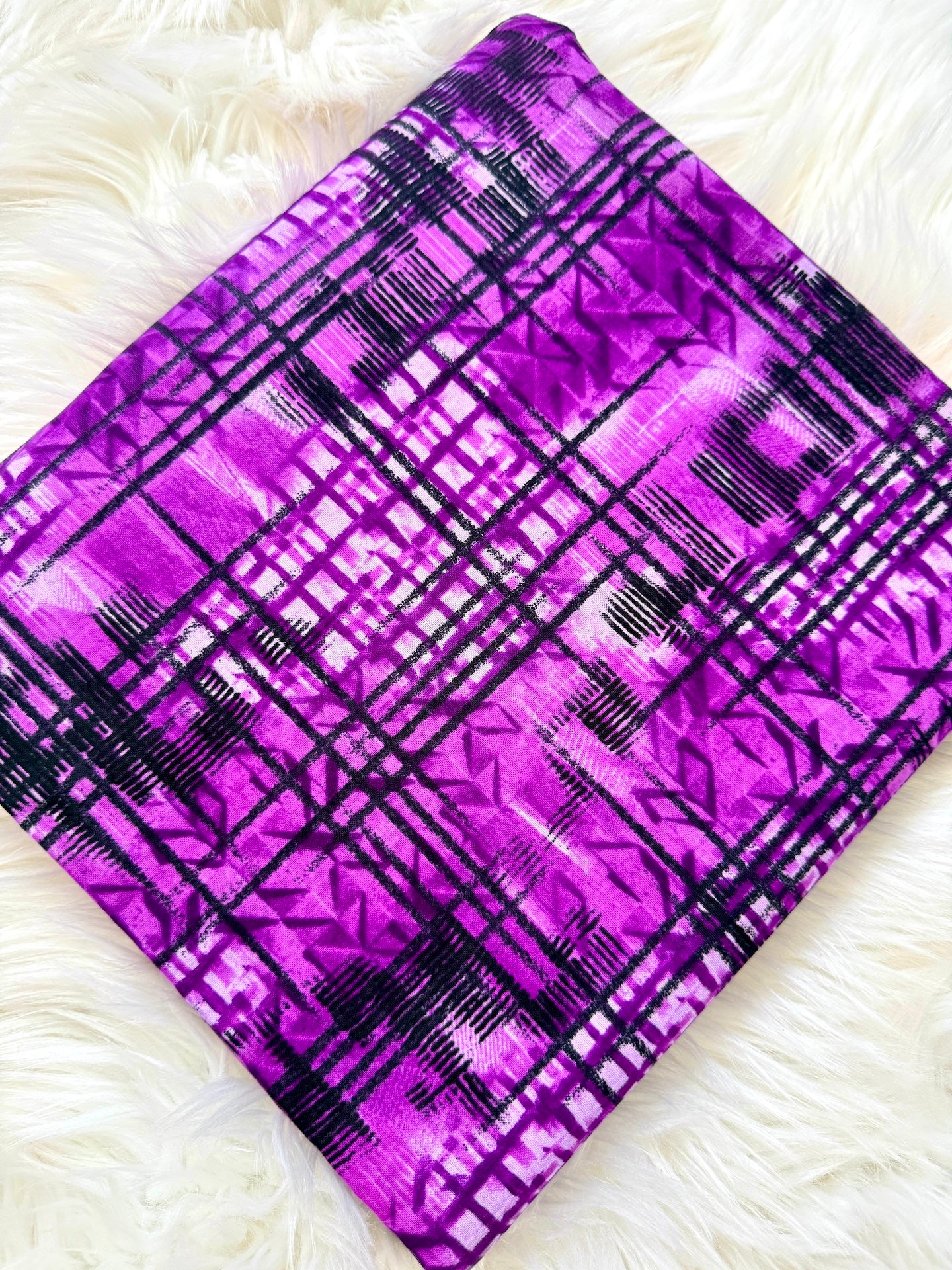 Purple fabric with black plaid pattern on a white fluffy surface