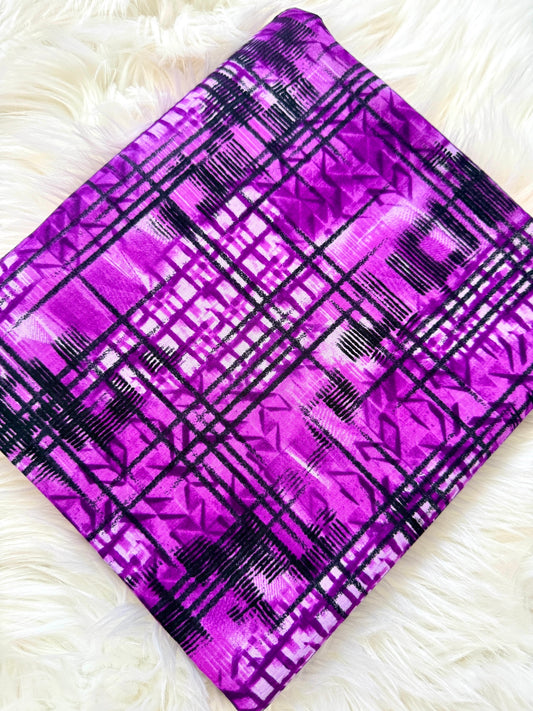 Purple fabric with black plaid pattern on a white fluffy surface