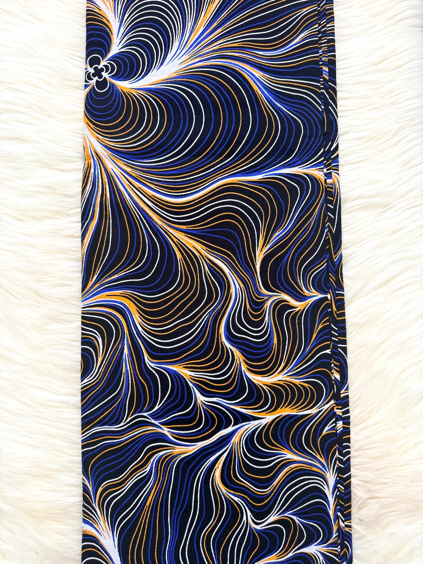 Marbled patterned fabric with blue and gold swirls on a textured white background