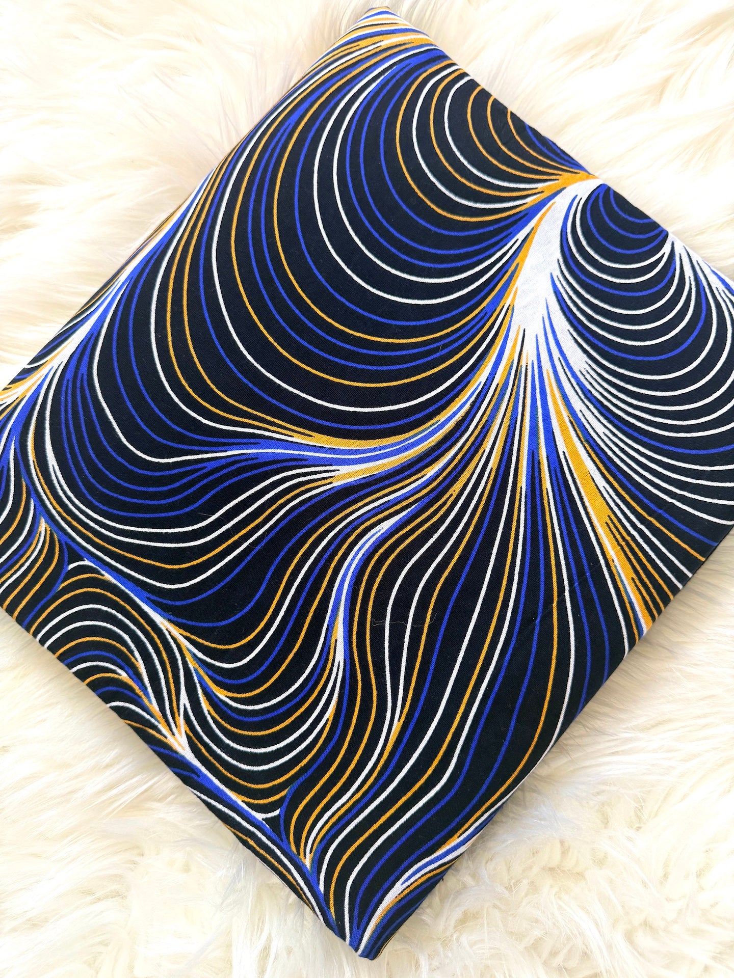 Fabric with blue and gold wavy pattern on a white textured background