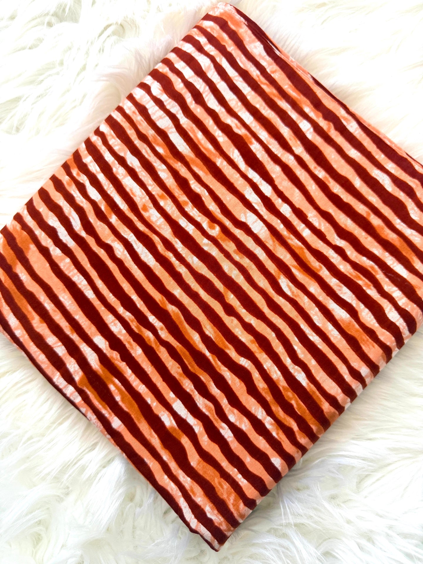 Fabric with brown and white striped pattern on a white fluffy surface