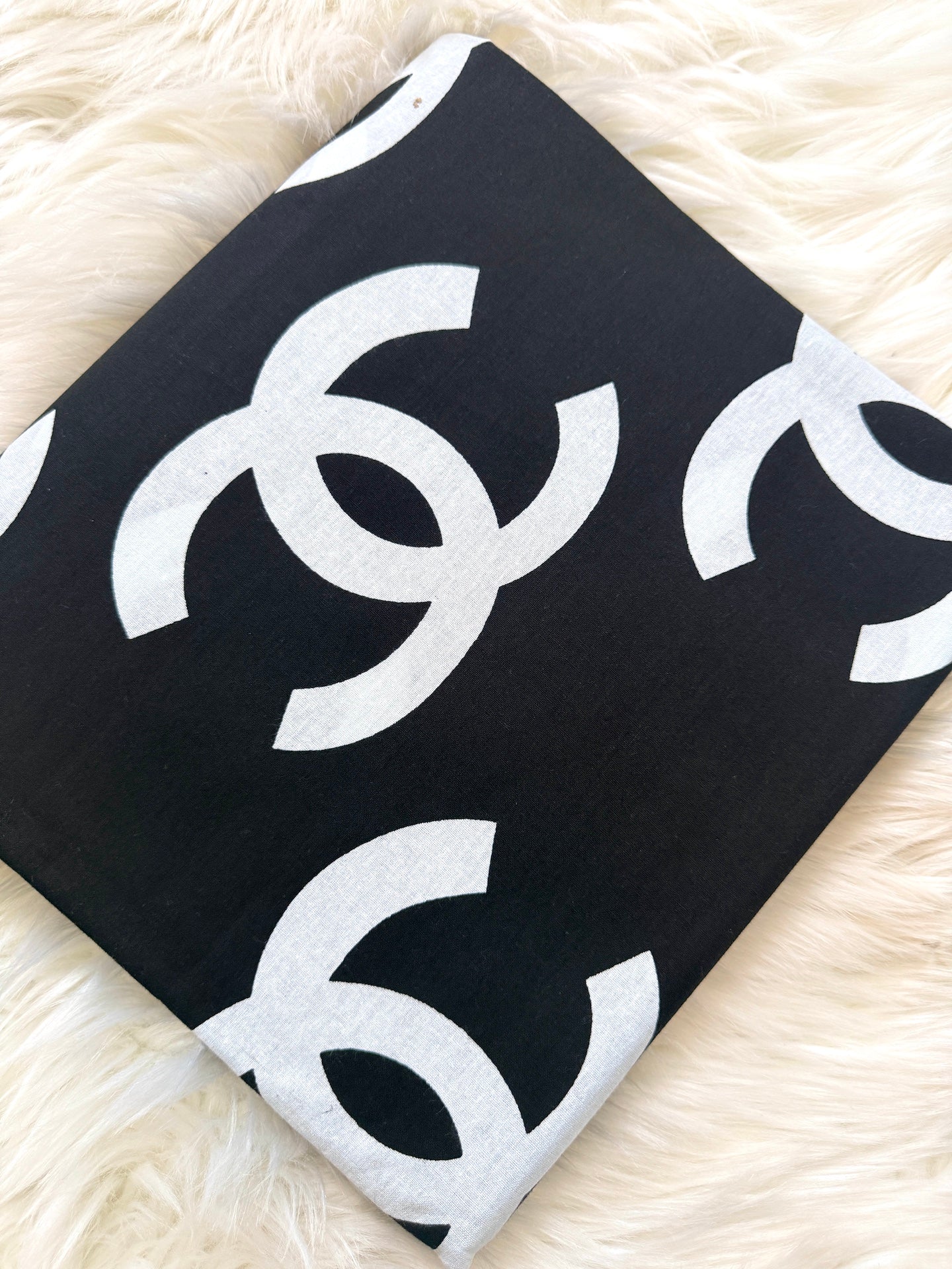 Black fabric with white 'CC' logo on a fluffy white surface