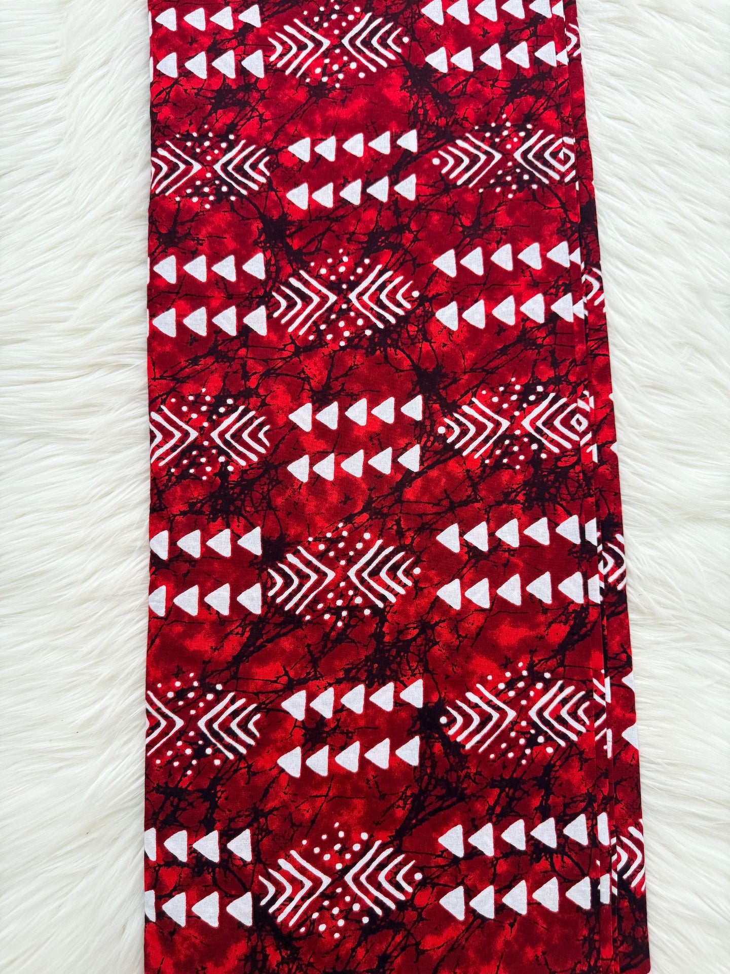 Red fabric with white geometric pattern on a white textured background