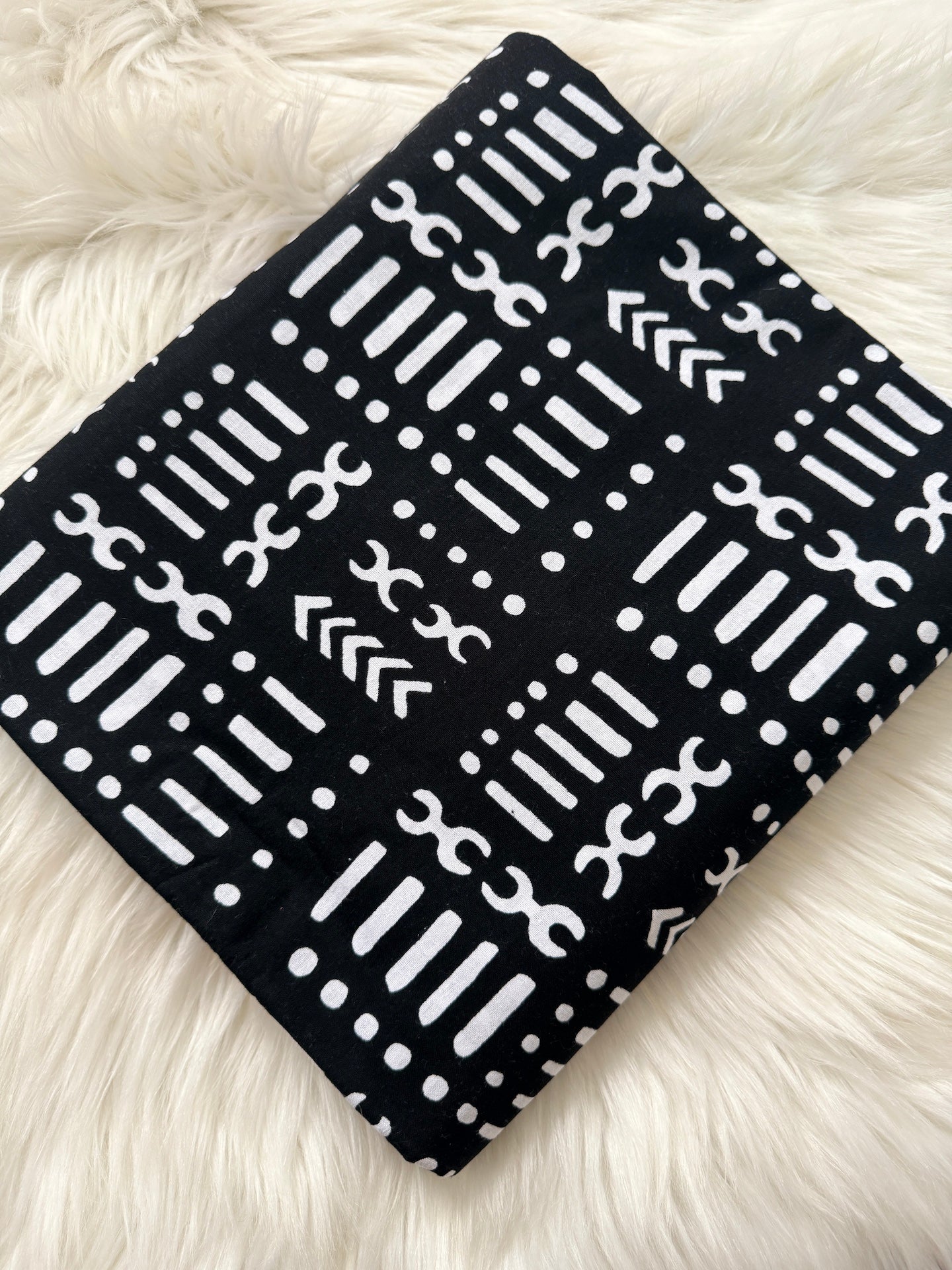 Black fabric with white geometric pattern on a white fluffy surface