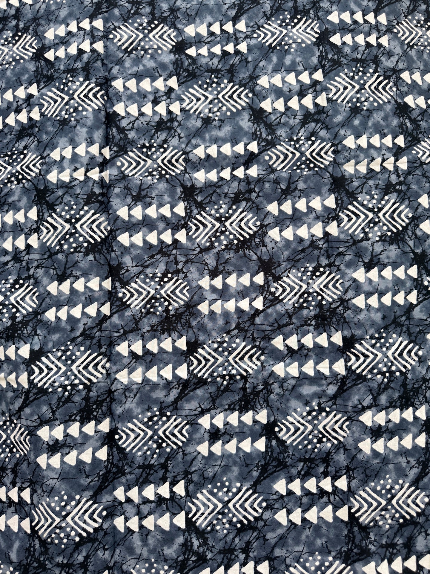 Patterned fabric with tribal design in black and white on a dark background