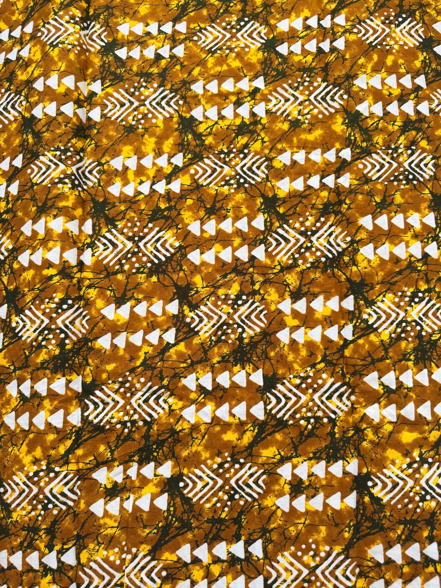 Patterned fabric with tribal design in gold, black, and white.
